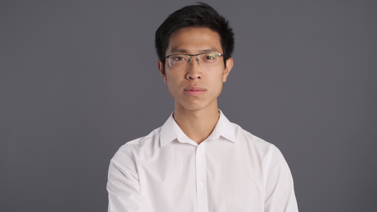 아시아인 남자가 카메라에 침 제스처를 하고 있습니다.