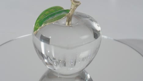 crystal glass apple on top of a mirror shinning light through