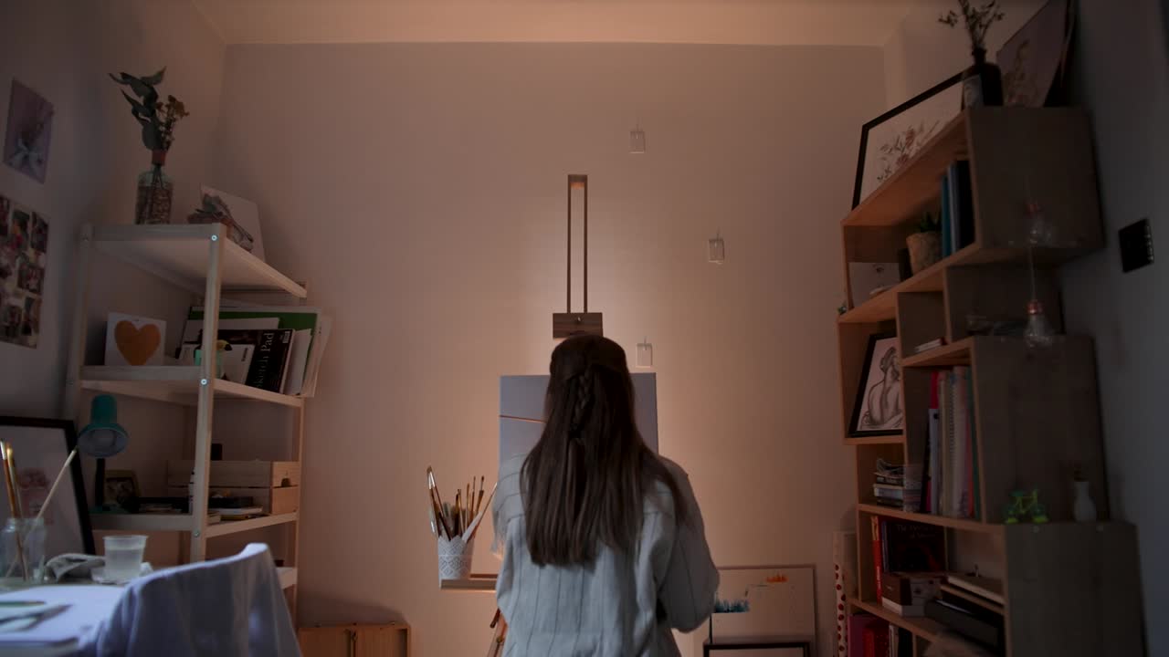 여성 예술가 가 캔버스 에 그림 을 그리고 있다