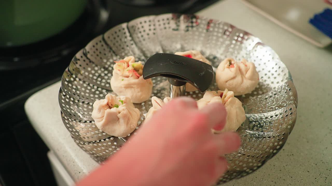 Putting fresh dumplings on the steamer and into a pot of boiling water