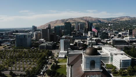 drone shot pushing past the american flag waving over downtown salt lake city, utah