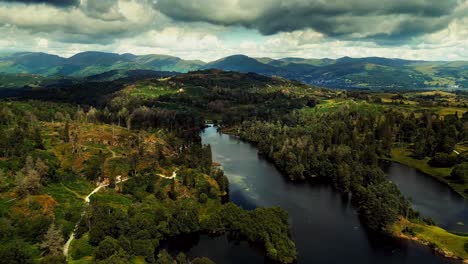 Ariel-footage-of-clouds-rolling-over-mountains-and-hills-with-trees-in-Lake-District,-Cumbria,-UK