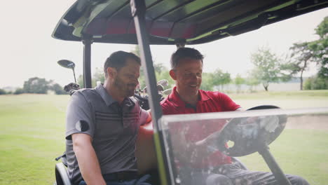 two mature male golfers in golf buggy on fairway discussing scorecard