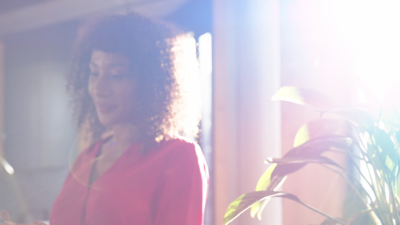 Smiling woman in bright office, standing near plant, enjoying sunlight
