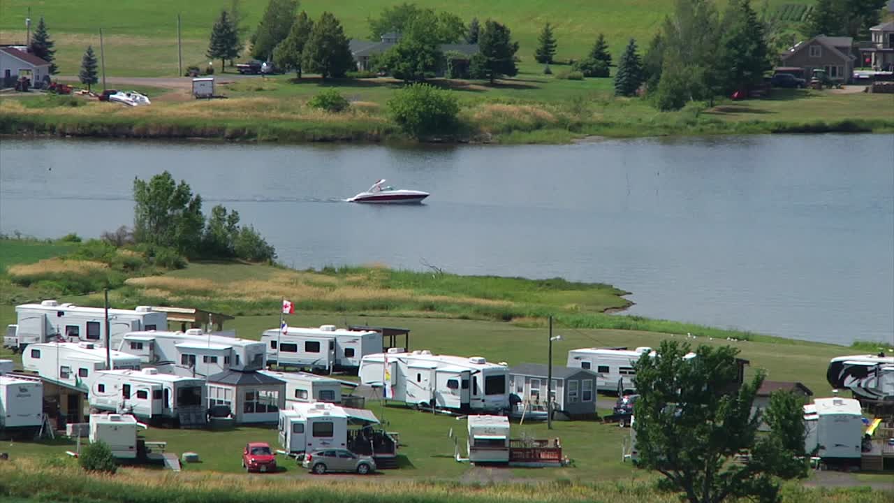 A speedboat slowly goes up the Bouctouche River near some trailers on the shore near Sainte-Marie-de-Kent in New Brunswick, Canada