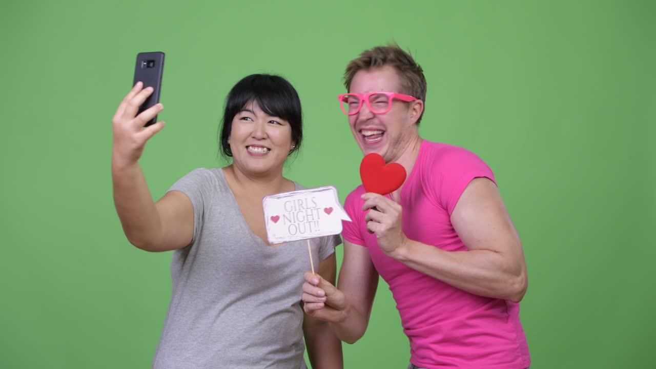 Overweight Asian woman and young gay man taking selfie together