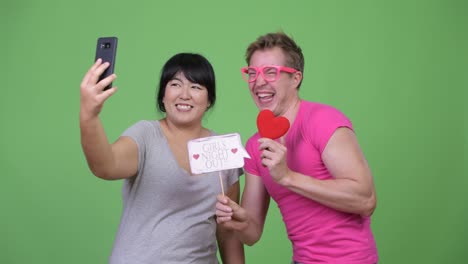 overweight asian woman and young gay man taking selfie together