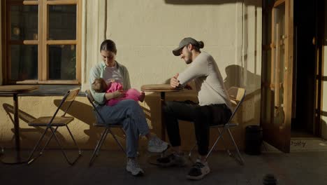 a young couple enjoying a day out at a cafe with their baby