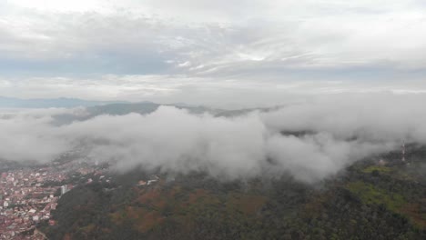 Pull-front-above-field-approaching-to-a-small-town-in-a-cloudy-day-in-Colombia