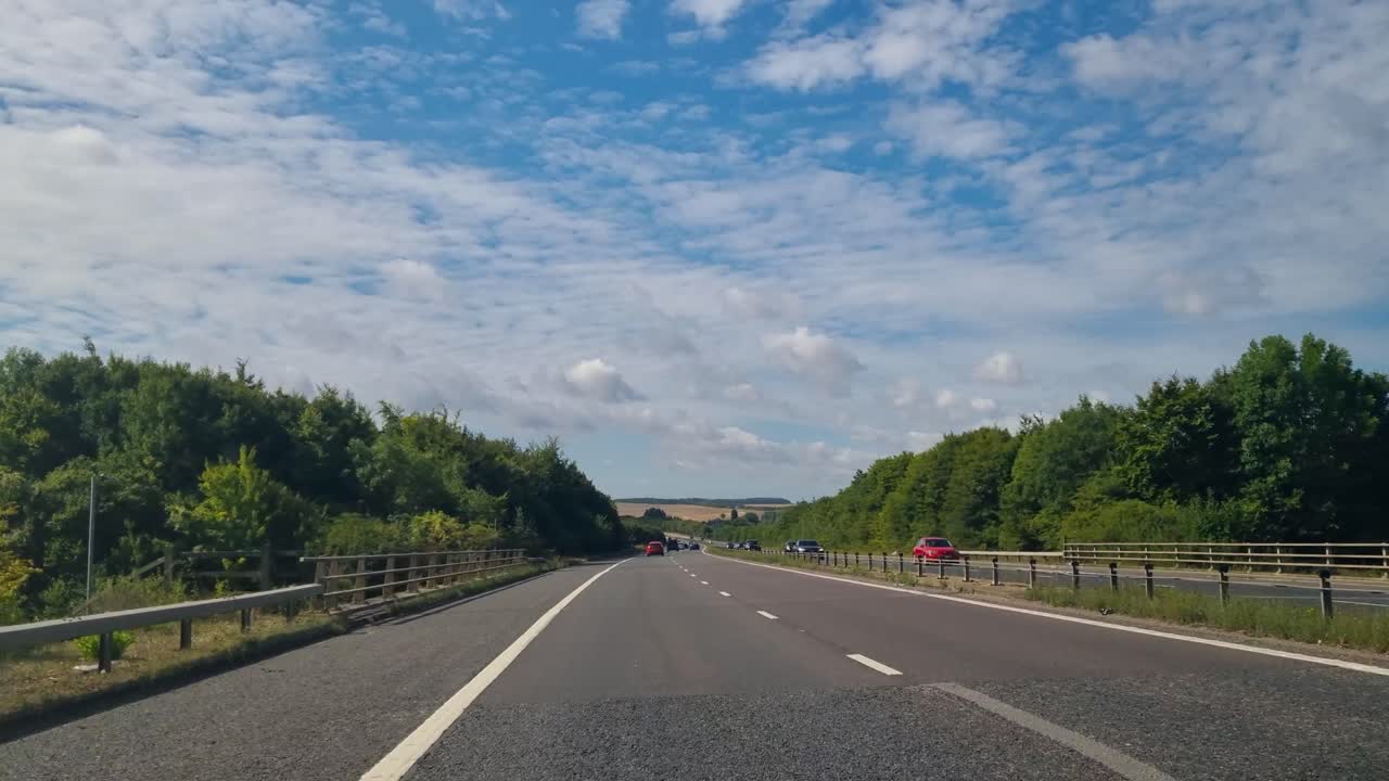 Passenger POV from a car driving along a highway in the East Midlands, UK, showcasing open roads and the lush summer landscape on a sunny day