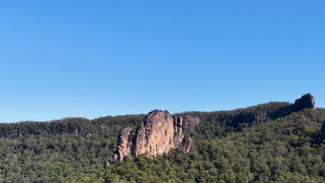 a serene landscape showcasing nimbin rocks under clear blue skies, captured in steady daylight with minimal camera movement