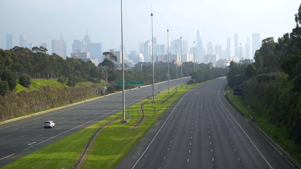 el automóvil conduce por una carretera inquietantemente vacía durante el bloqueo de covid-19: filmado en melbourne, australia, pero puede representar muchos horizontes urbanos y el impacto del coronavirus en todo el mundo
