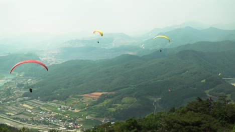 tandem paragliding against mountains in danyang city, south korea, very cloudy and dusty after rain