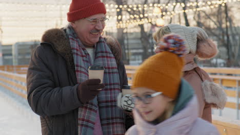 older couple enjoying coffee at winter ice rink