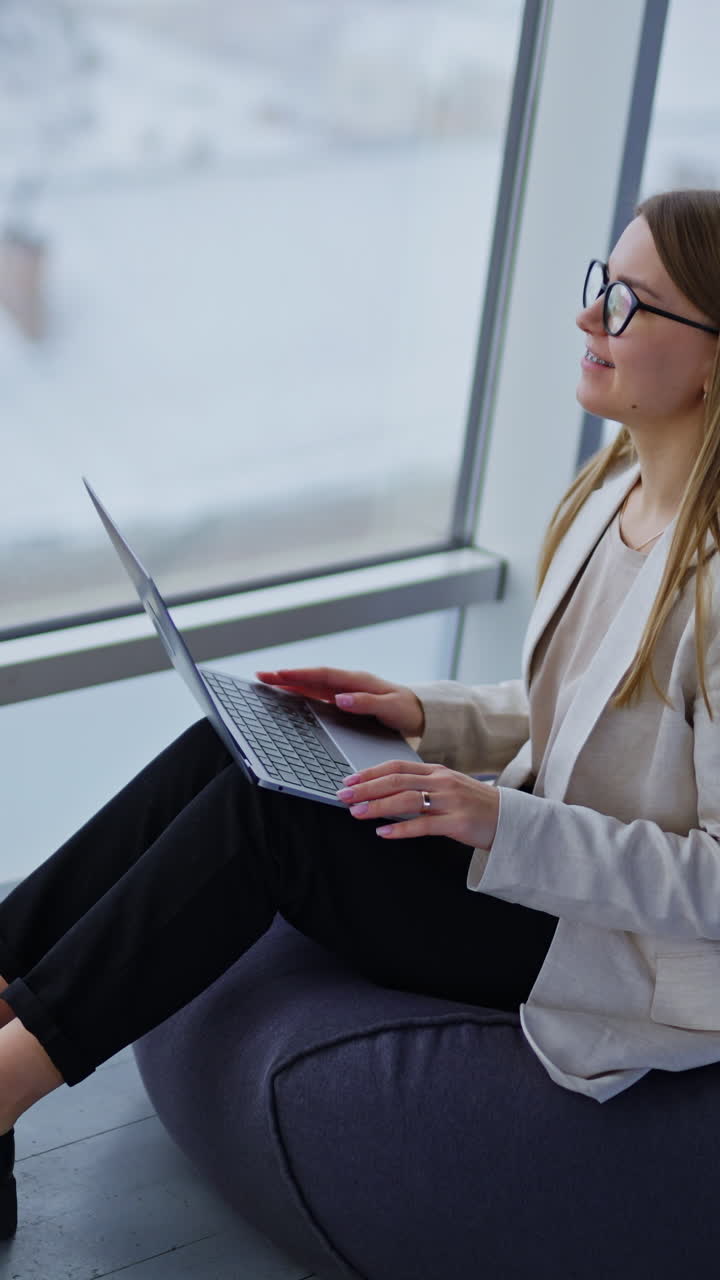 Bella donna d'affari che guarda lo schermo del laptop in un luogo di lavoro remoto. Donna fiduciosa che lavora in un ufficio. Video verticale.