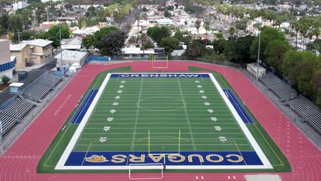 Crenshaw-Cougars-Campo-De-Fútbol-Y-Pista,-Antena-Ascendente-Sobre-La-Ciudad,-Estadio-Vacío