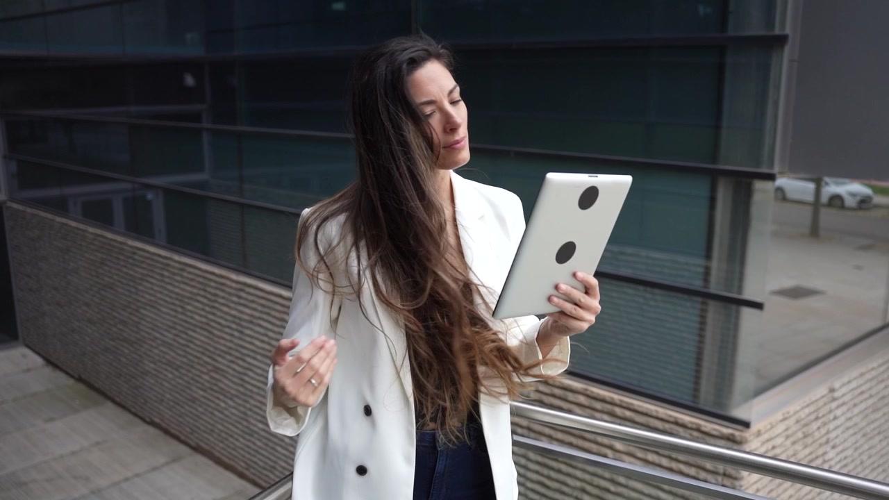 Una donna professionista che usa con sicurezza un tablet all'aperto in un vivace contesto urbano.