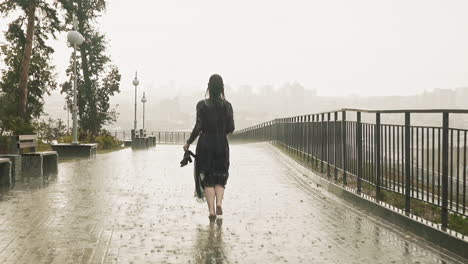 graceful woman runs holding shoes along promenade at rain