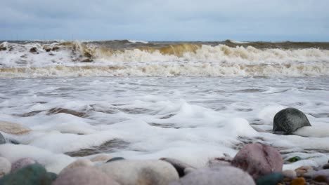 foamy breaking ocean surf pebble beach shoreline tide soothing multicoloured stones dolly right