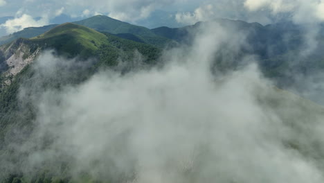 volando a través de nubes blancas y esponjosas por encima de los picos verdes de las montañas