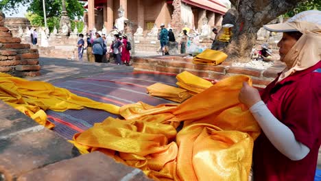 monk folding golden robes at ayutthaya temple