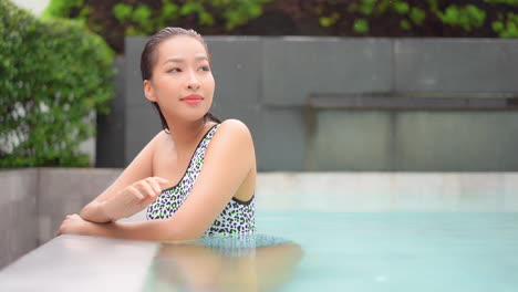 Close-up-of-a-pretty-young-woman-lounging-in-a-luxury-pool-as-the-rain-falls