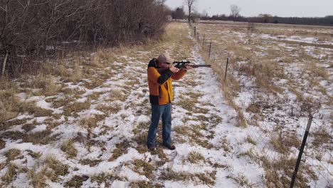 Hunter-with-sniper-rifle-aiming-looking-for-targets,-close-up-aerial-view