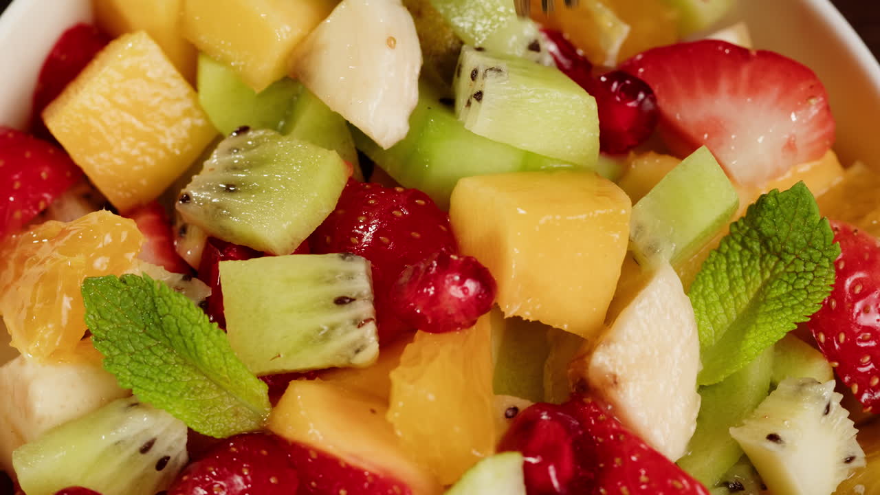 Fork Picking Up a Piece of Fresh Fruit from a Colorful Salad