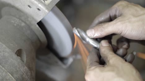 men working sharpening broken drills on a diamond wheel in the industrial factory. slow motion