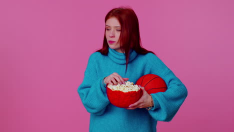 Redhead-young-woman-basketball-fan-eating-popcorn-doing-winner-gesture,-celebrating-victory-win