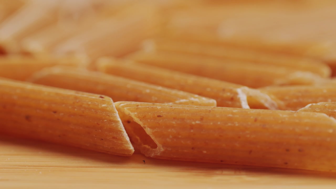 Bio-Vollkornnudeln, Makkaroni aus Hartweizengrieß, ungekochte Penne Rigate in einer Holzschale. Hochwertiges 4K-Filmmaterial