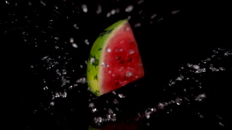 slow motion shot of falling piece of watermelon on wet surface with black background