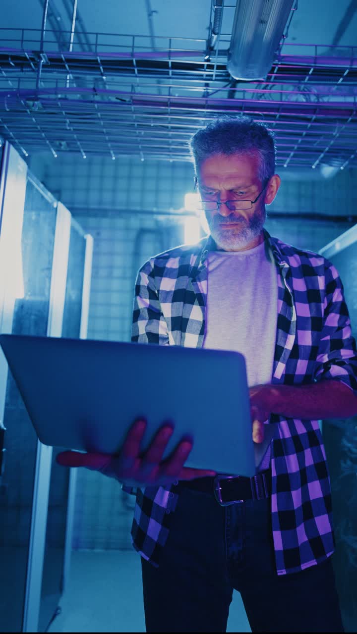 Man working on a laptop in a server room