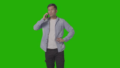 Studio-Shot-Of-Angry-Casually-Dressed-Young-Man-Talking-On-Mobile-Phone-Against-Green-Screen-1