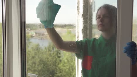 cleaning company worker or housewife cleaning windows using detergent and window cleaning cloth. washing windows with a spray bottle.