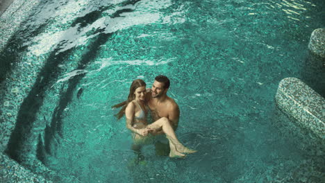 Above-view-attractive-couple-relaxing-at-pool.-Happy-couple-enjoying-luxury-pool
