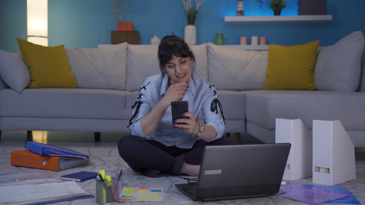 una mujer que trabaja en una oficina en casa se alegra por teléfono.