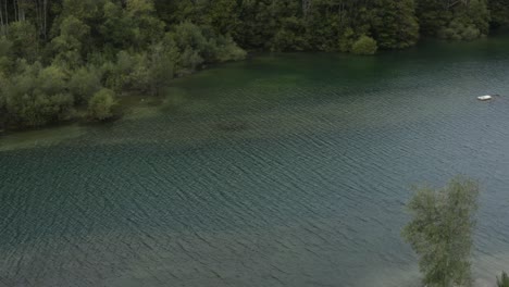 Freibach-reservoir-in-the-south-Austrian-Alps-with-calm-water-and-small-boats,-Aerial-pan-right-reveal-shot