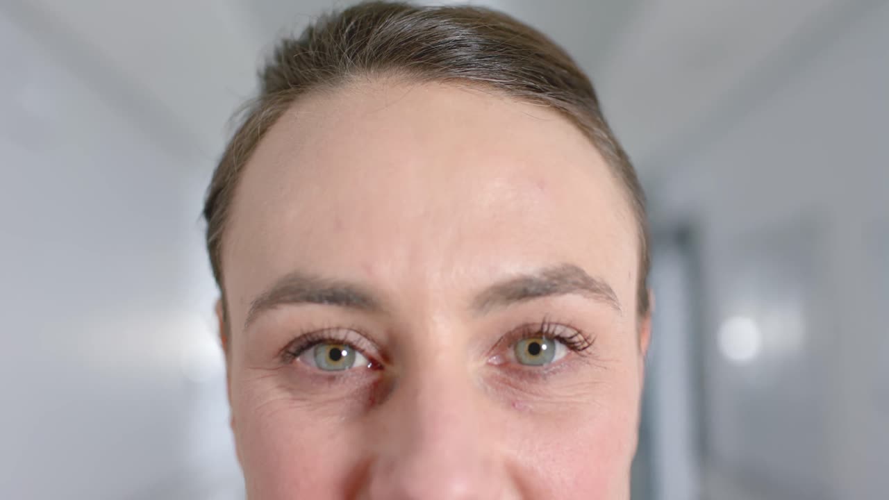 복도 에서 카메라 를 보고 있는 행복 한 백인 여성 의사 의 초상화, 느린 동작