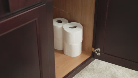 man stockpiling toilet paper in preparation for covid-19, man hoarding toilet paper in bathroom cabinet, white caucasian male filling cabinet with tp for coronavirus in the us worldwide pandemic panic