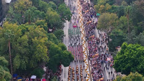 ascending aerial shot of the day of the dead parade held on paseo de la reforma, with a bird's-eye view of the parade ending with a direct shot of chapultepec castle in mexico city