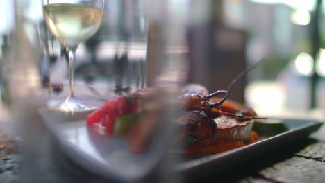 plated food sits near a glass of white wine