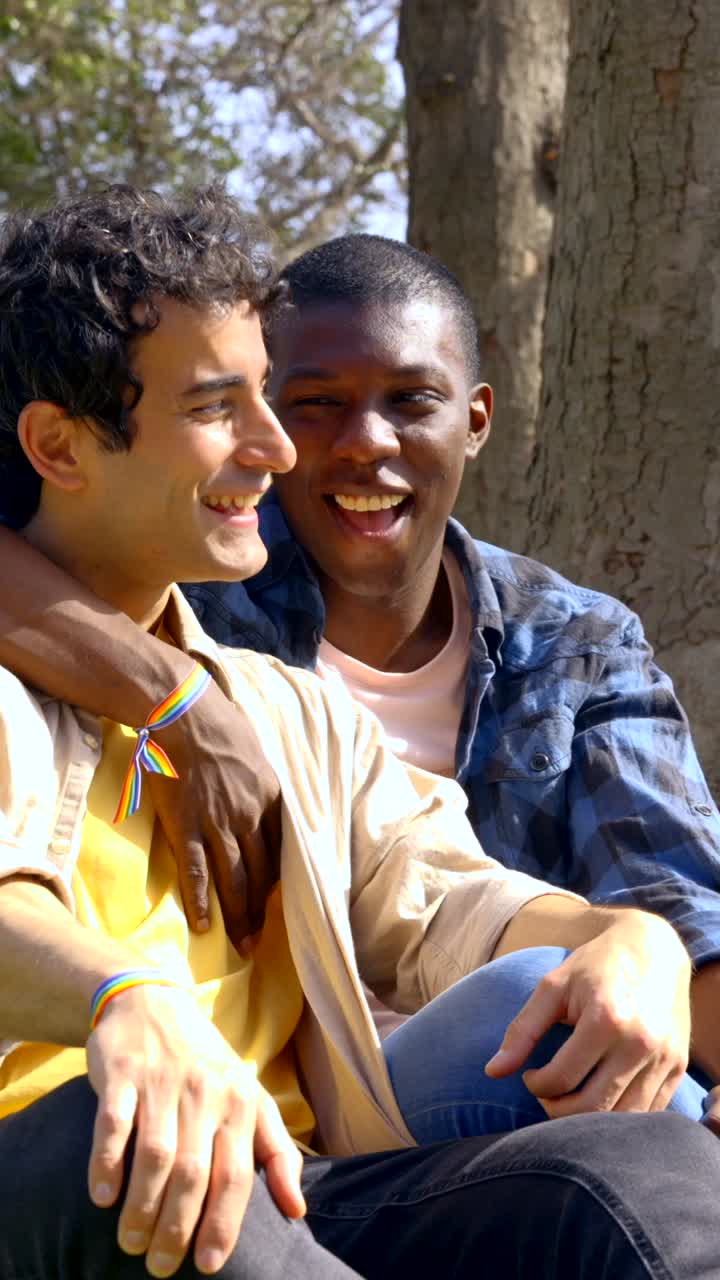 Two men, one African-American, the other Caucasian, in love with LGBTQ pride bracelets and arm around each other