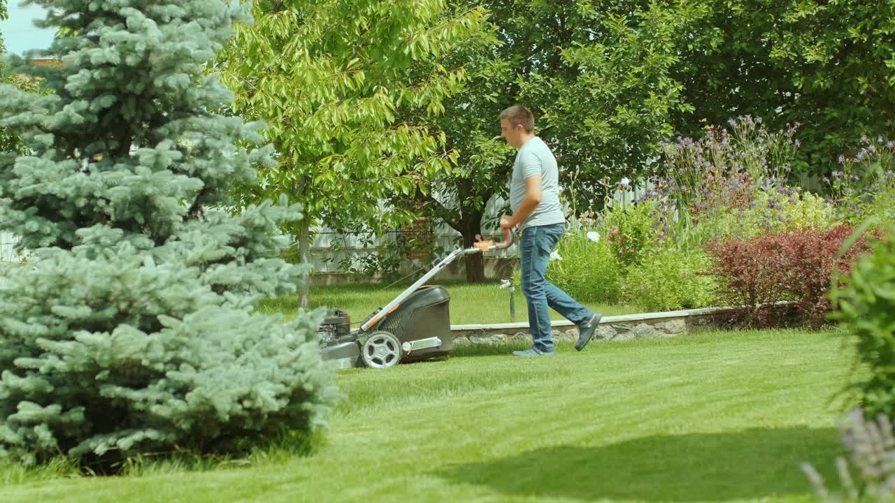 잔디를 는 잔디 기. 정원 활동. 빛 정원에서 가솔린 구동 잔디기와 함께 잔디을 는. 정원에서 잔디 자르기 기계와 함께 일하는 정원사. 잔디자리 기
