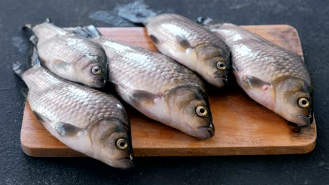 cooking fish. fresh small carps on the table on a wooden board close-up.