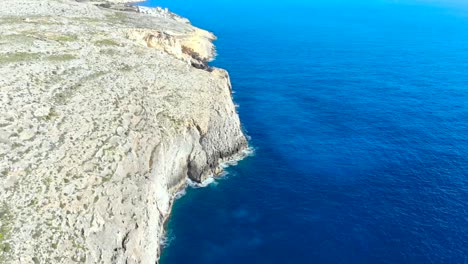 drone shot over rocks and cliffs in the mediterranean sea of malta