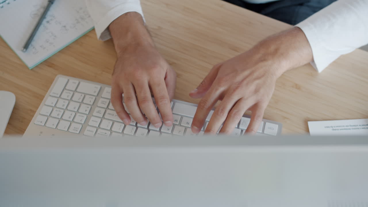 Person Working on a Computer at a Wooden Desk