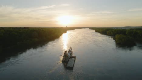 Aerial-view-towards-a-river-sand-dredging-ship,-sunny-evening-in-Missouri,-USA---tilt,-drone-shot