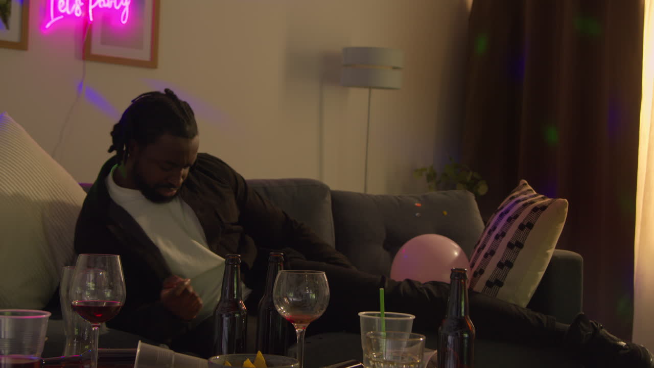 Man Lying On Sofa Recovering From Drinking Alcohol At House Party Suffering With Hangover 2