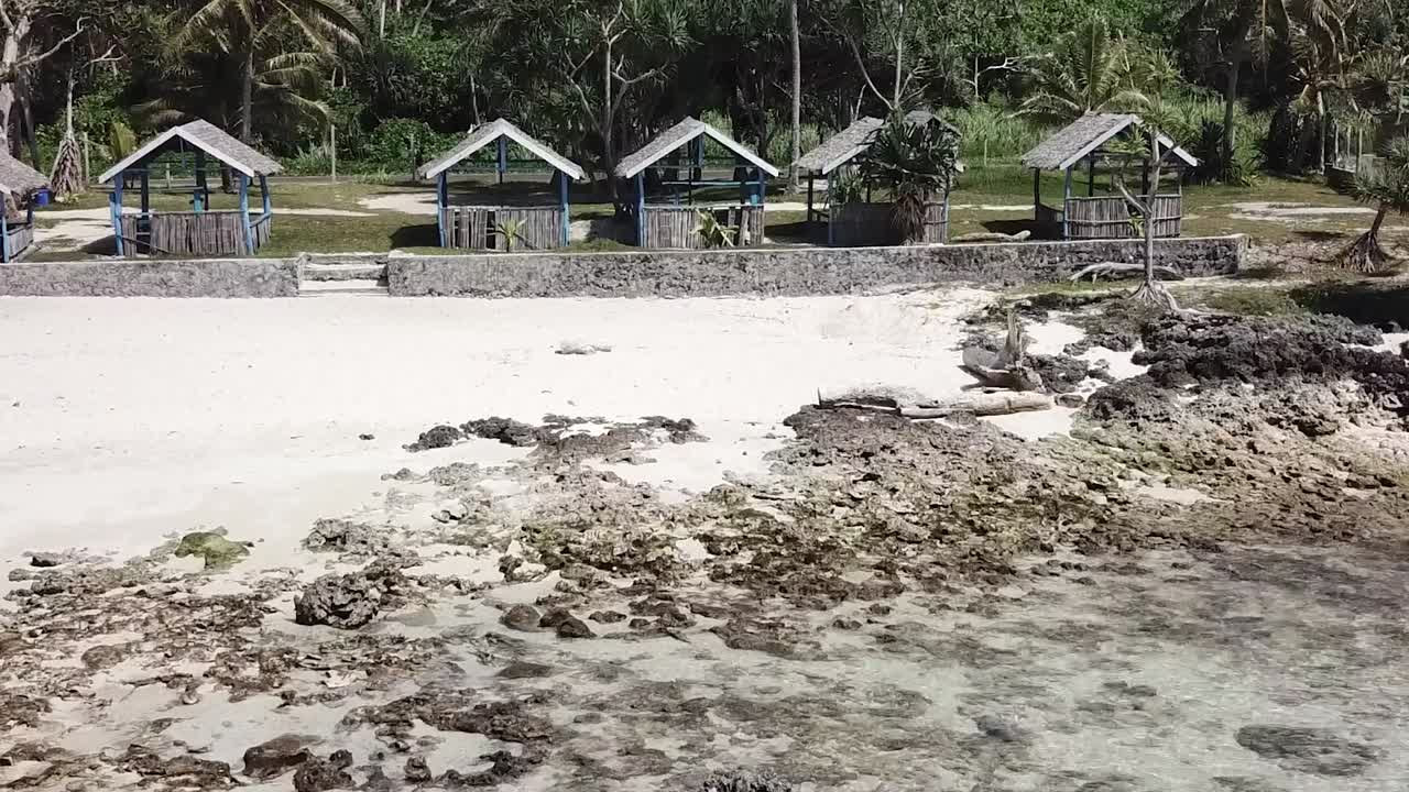 하얀 모래와 맑은 물 위의 해변 오두막을 향해 날아갑니다.